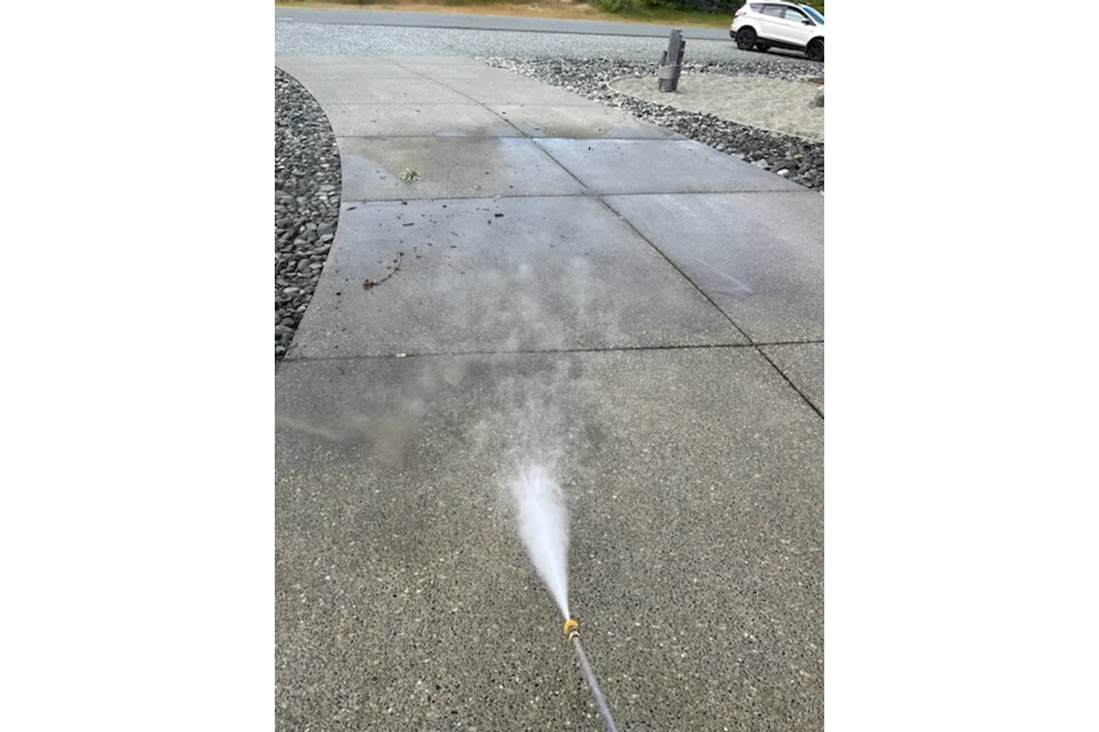 a white sprinkler spraying water on a sidewalk