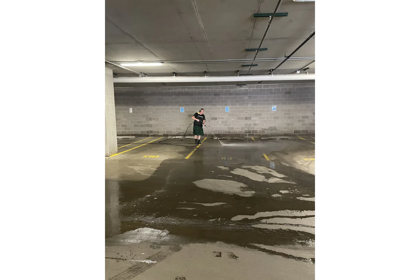 a man holding a broom in a parking garage
