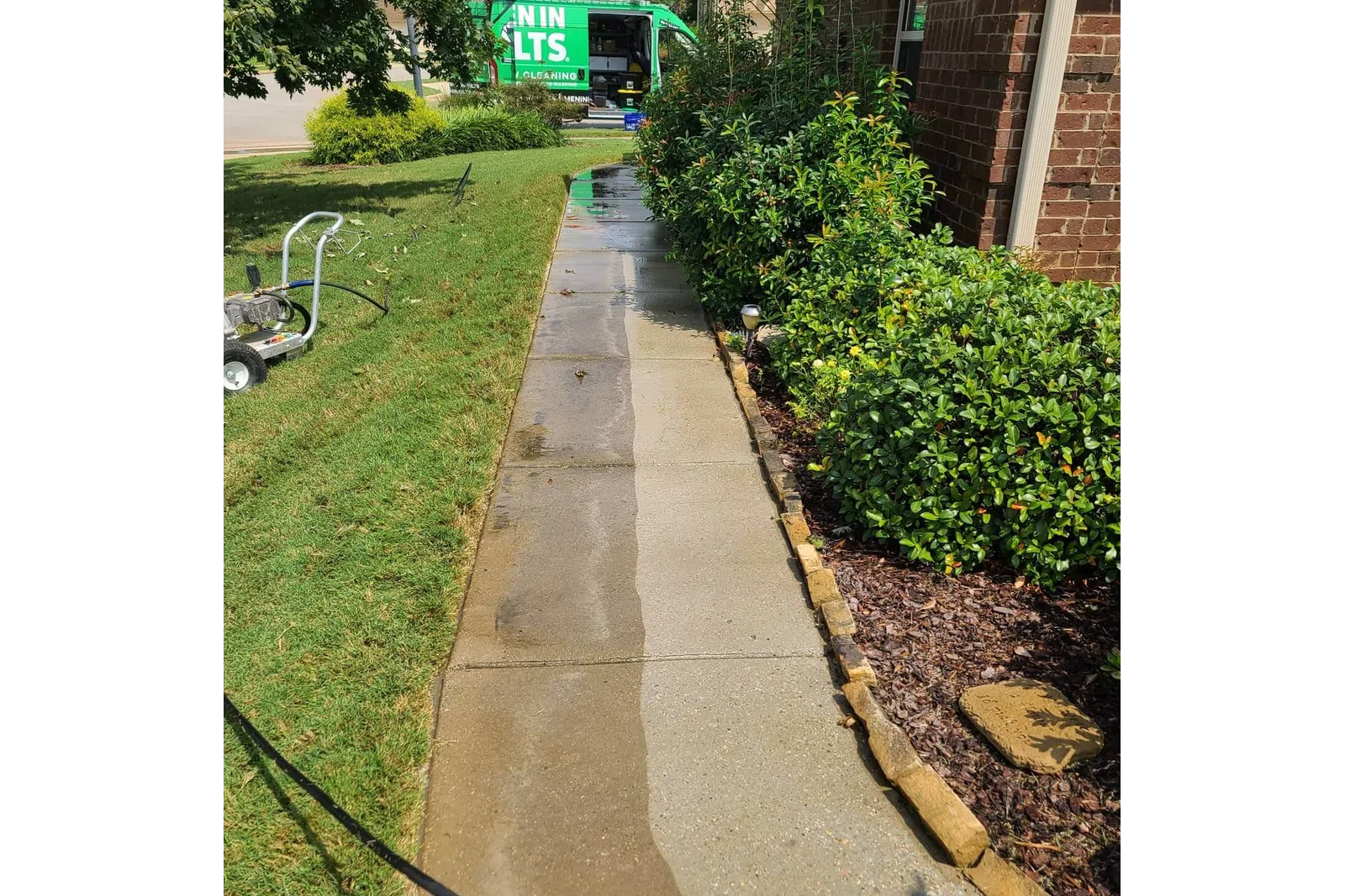 a sidewalk with bushes and a bus