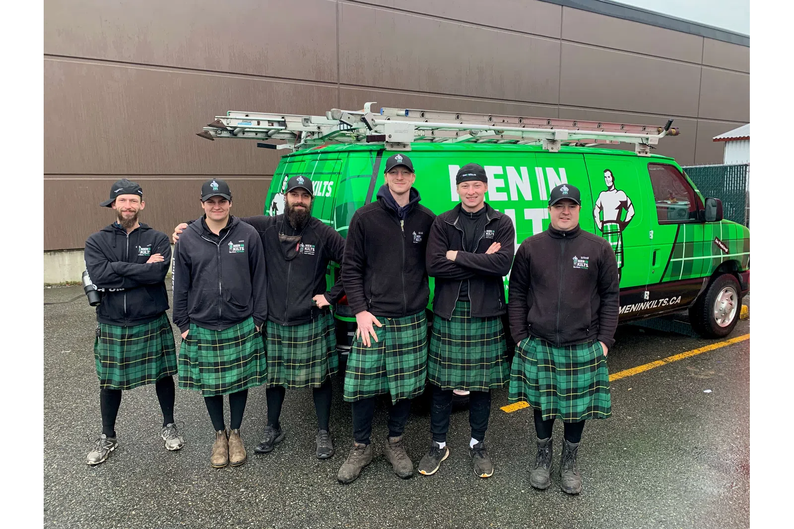 a group of men in kilts standing in front of a green truck