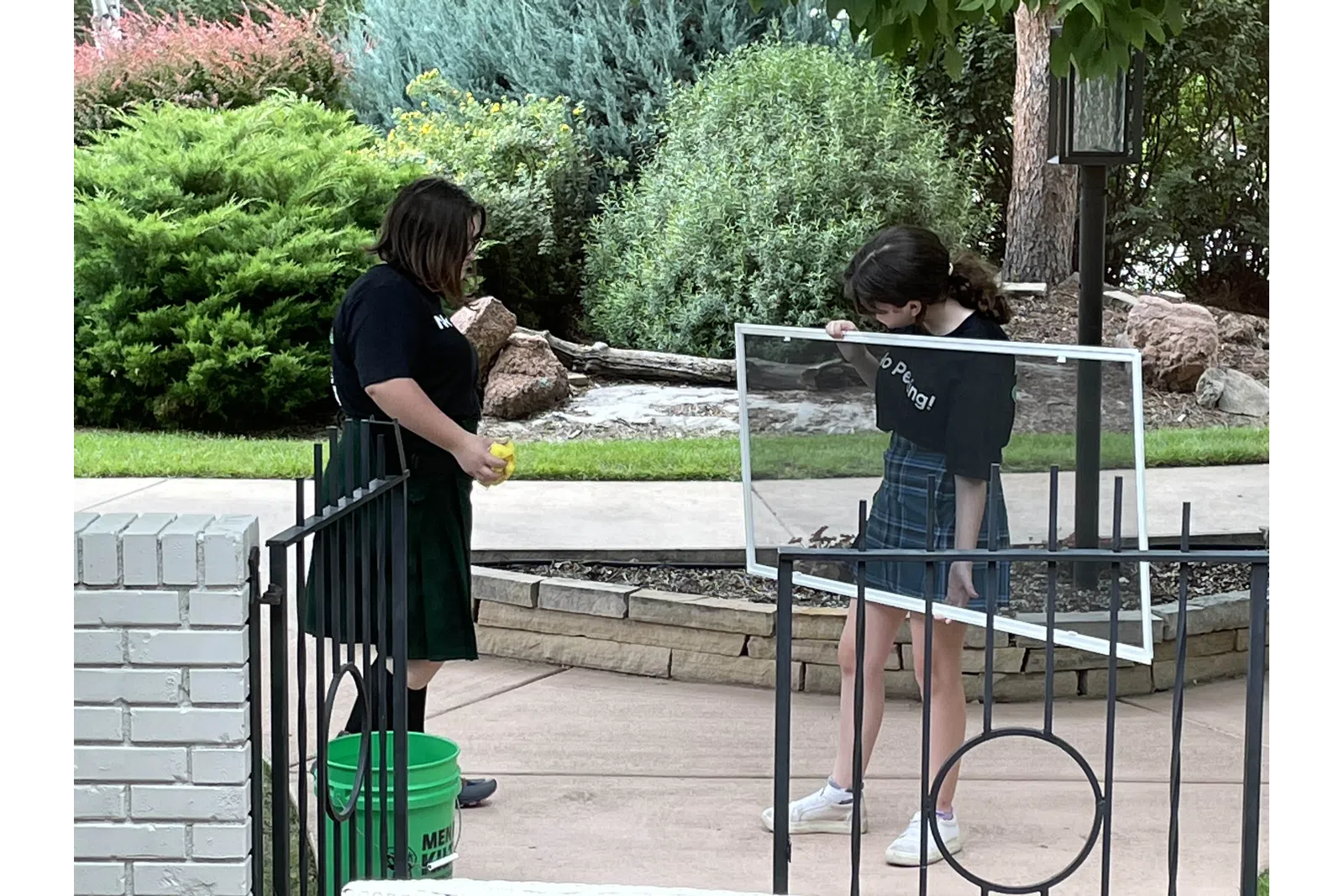 a couple of girls standing on a metal fence