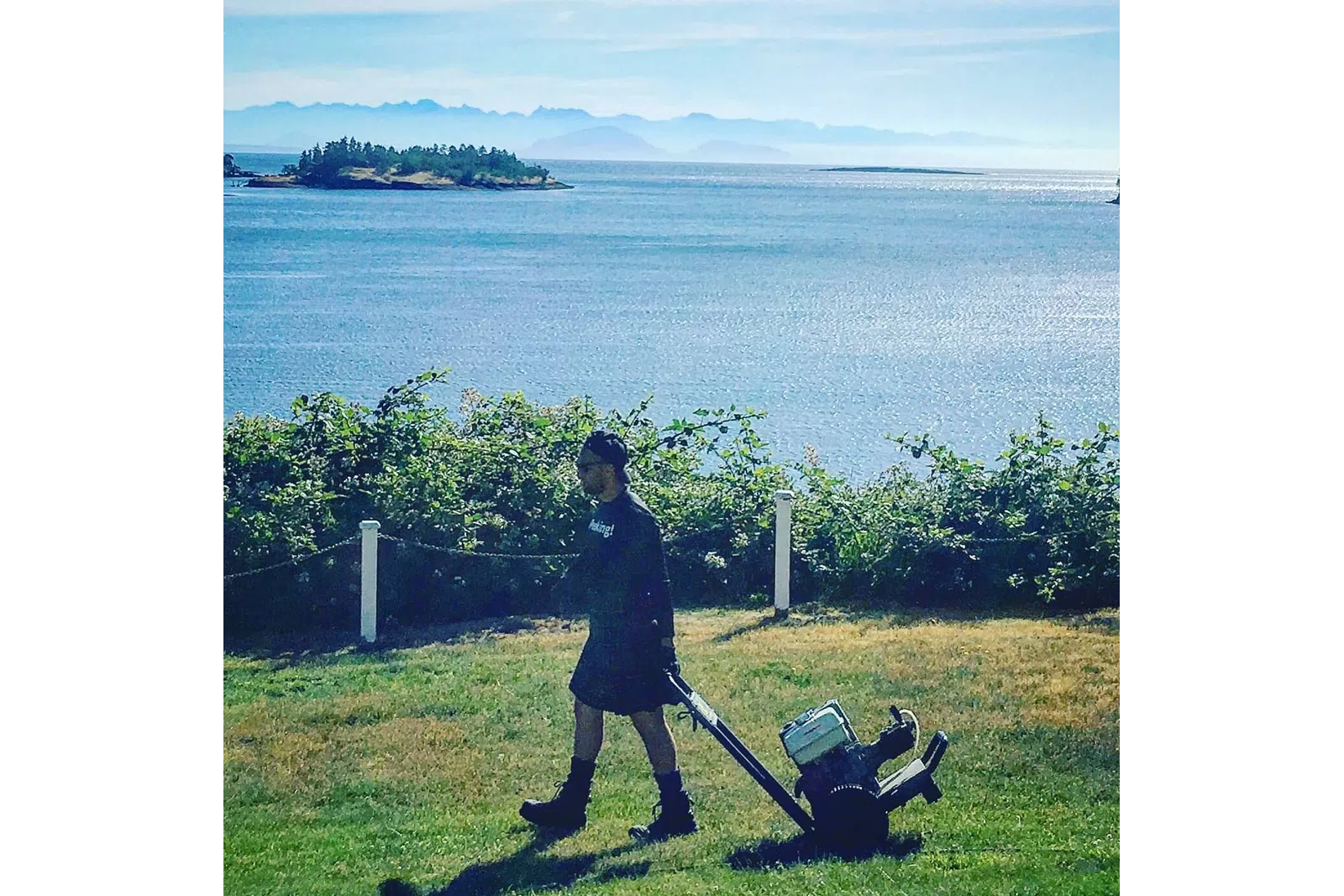 a person standing next to a bush with a body of water in the background