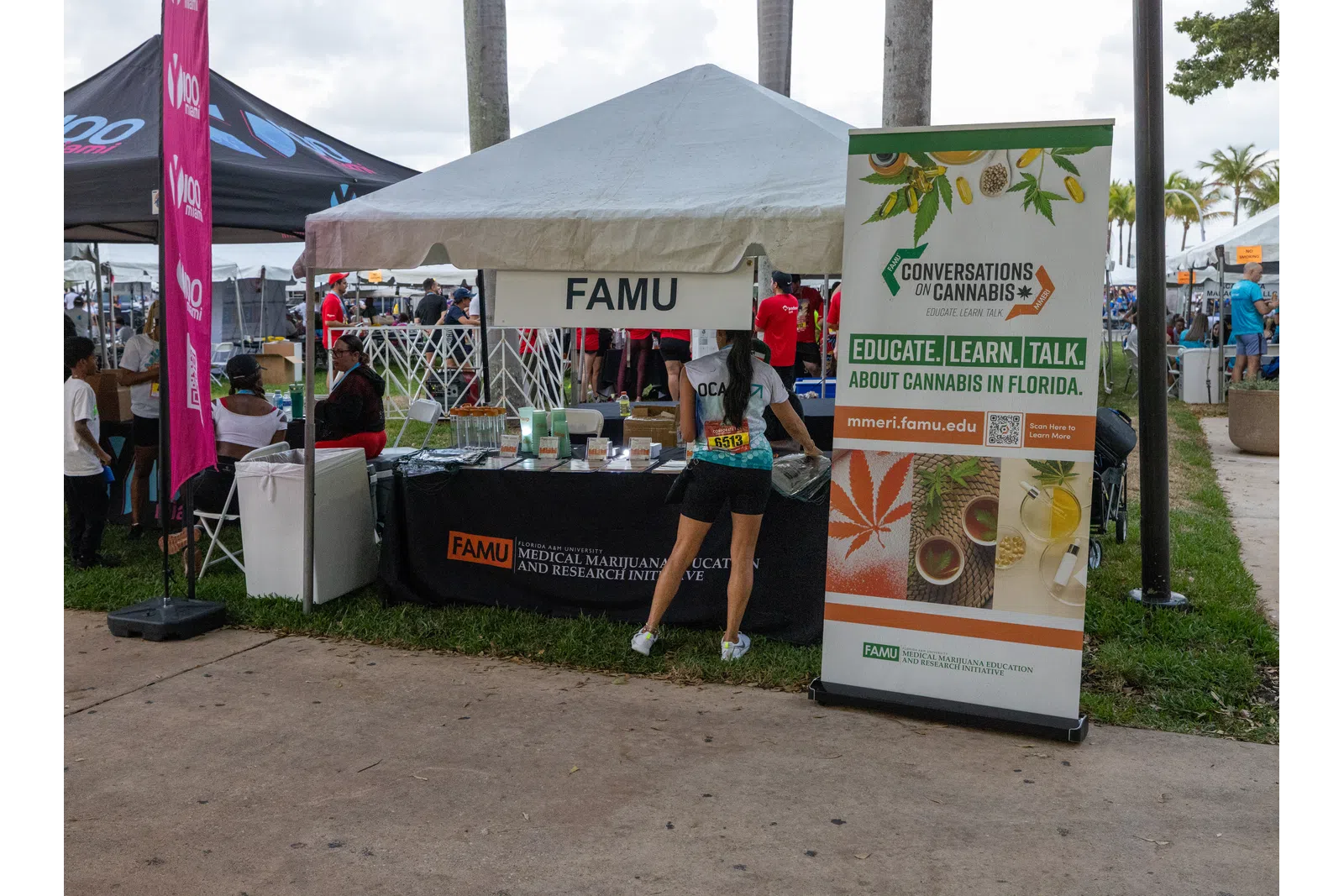 FAMU booth at an outdoor event promoting cannabis education and research with informational banner and visitors.