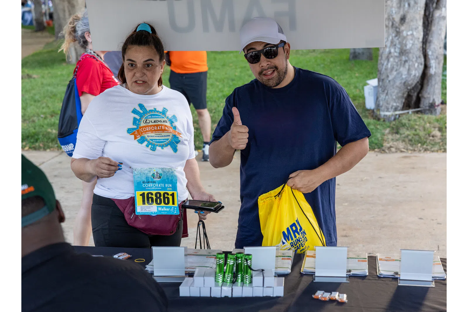 Participants at a corporate run event registration table with race bibs and giveaways outdoors