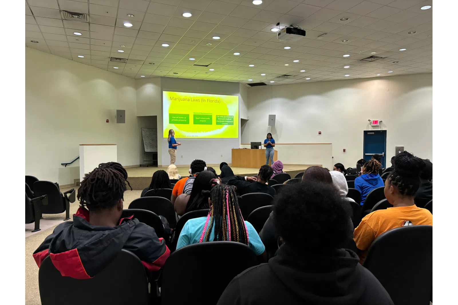 a group of people sitting in a room with a projection screen