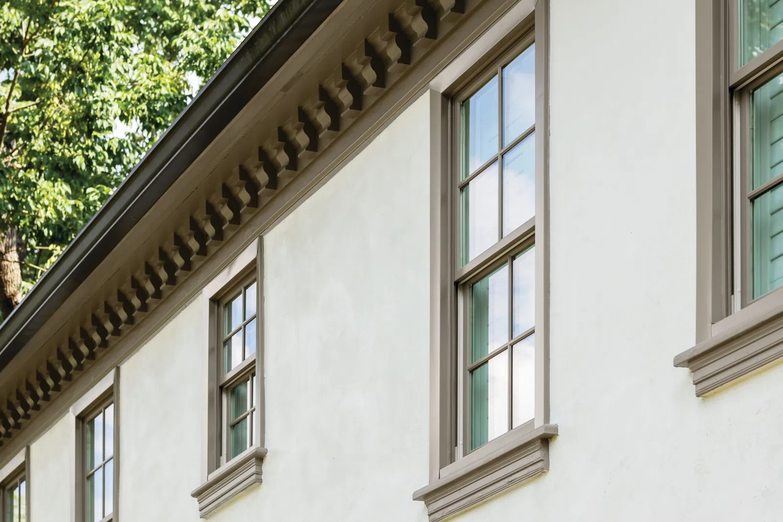 Close-up of custom double hung windows on a beige exterior, highlighting high-quality residential window replacement.