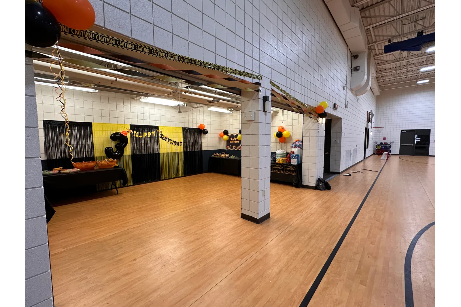 Wide view of a decorated event space with balloons and tables set for a celebration.
