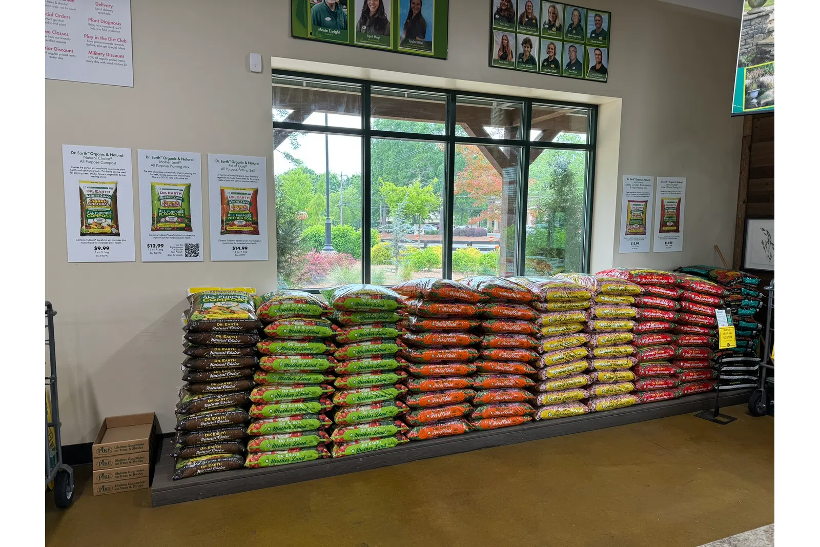 Stacks of colorful Dr. Earth's organic gardening soil bags displayed indoors near large windows in a nursery.