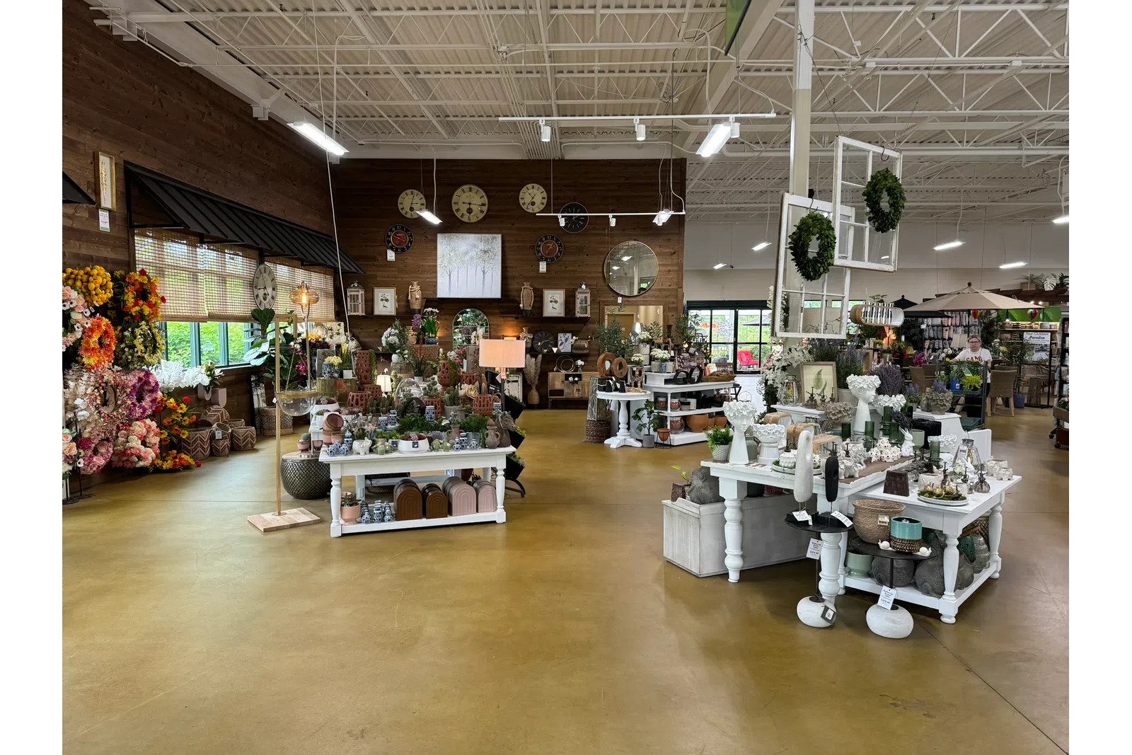 Interior view of a rustic gift shop with floral arrangements, decorative clocks, and home decor items on display.