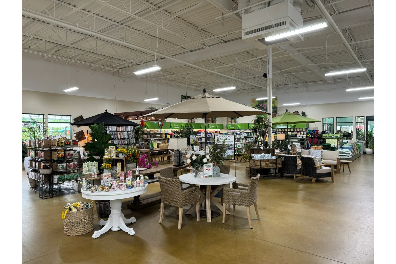 Indoor garden center with patio furniture, umbrellas, plants, and garden supplies on display under bright lighting.