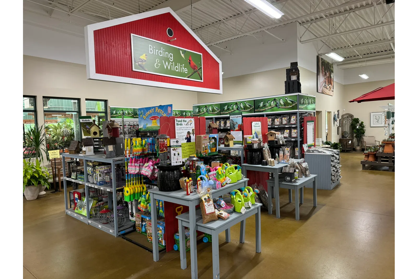 Indoor garden center section with birding and wildlife supplies, bird feeders, seed bags, and gardening tools.