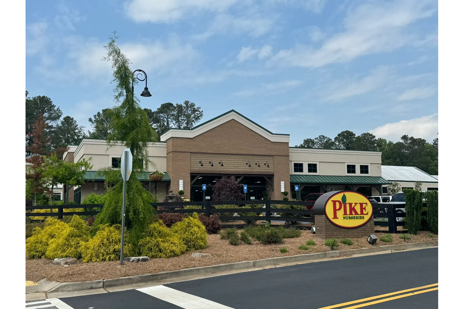 Pike Nurseries storefront with landscaping, green plants, and clear sky during daytime.
