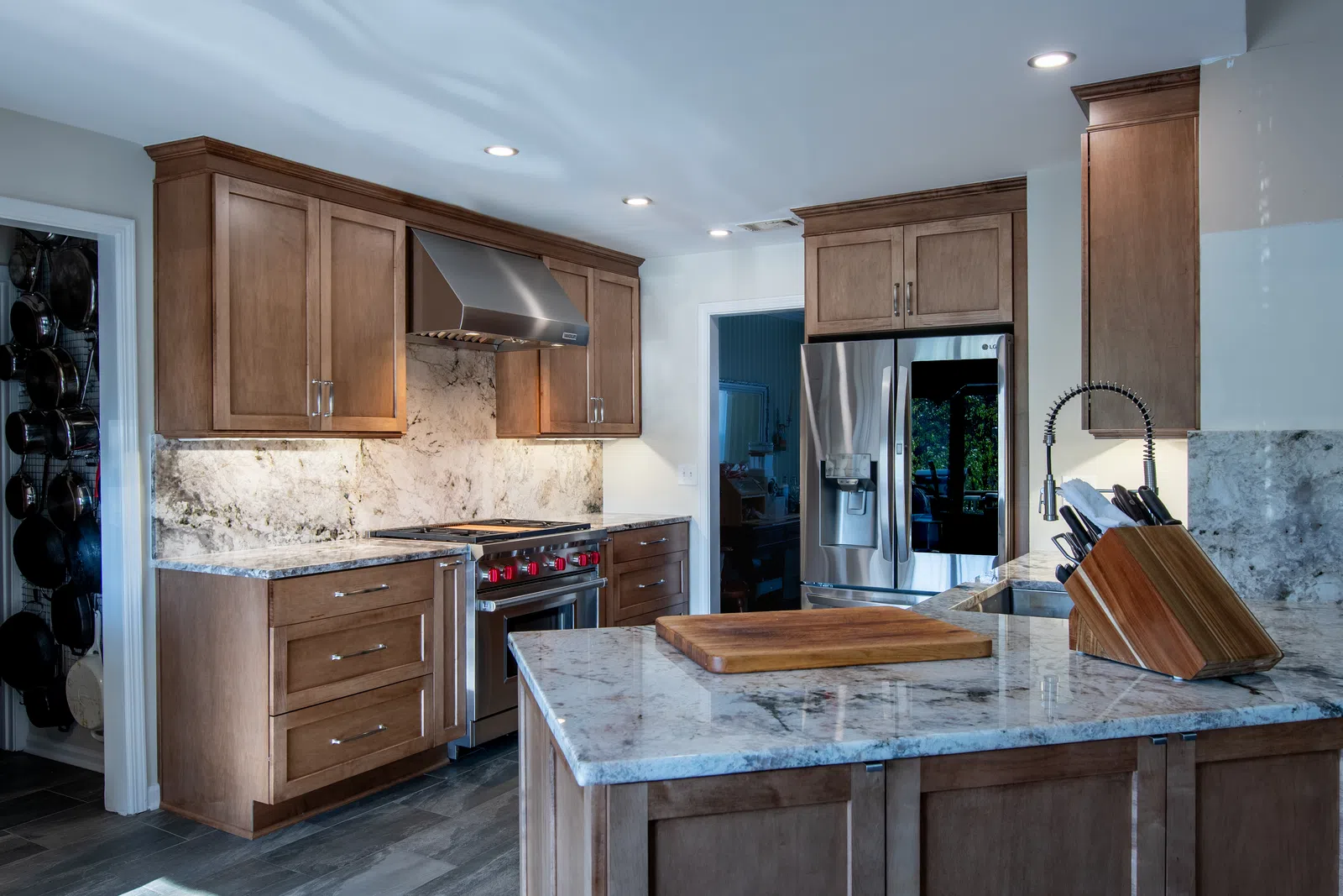 Modern kitchen with wooden cabinets, granite countertops, stainless steel appliances, and a large island with cutting board.