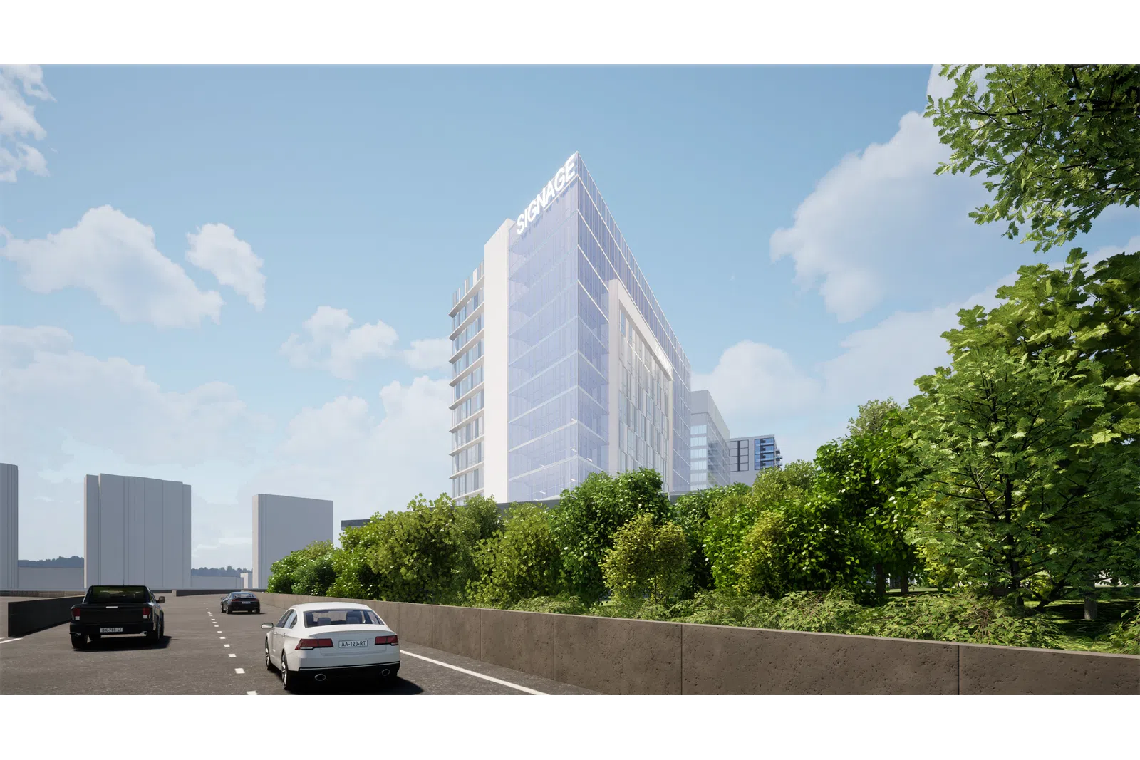 Modern glass office building with signage, surrounded by greenery alongside a busy street with cars under a blue sky.