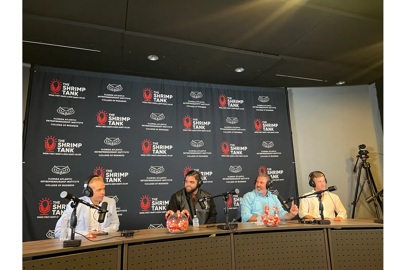 Four men with microphones speak at a panel for The Shrimp Tank at Florida Atlantic University College of Business