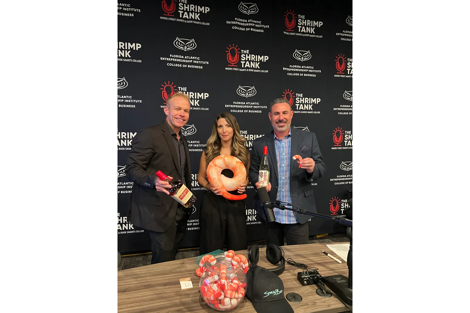 Three people hold shrimp-themed items in front of a backdrop with The Shrimp Tank and Florida Atlantic Entrepreneurship Institute logos, with overlaid text.
