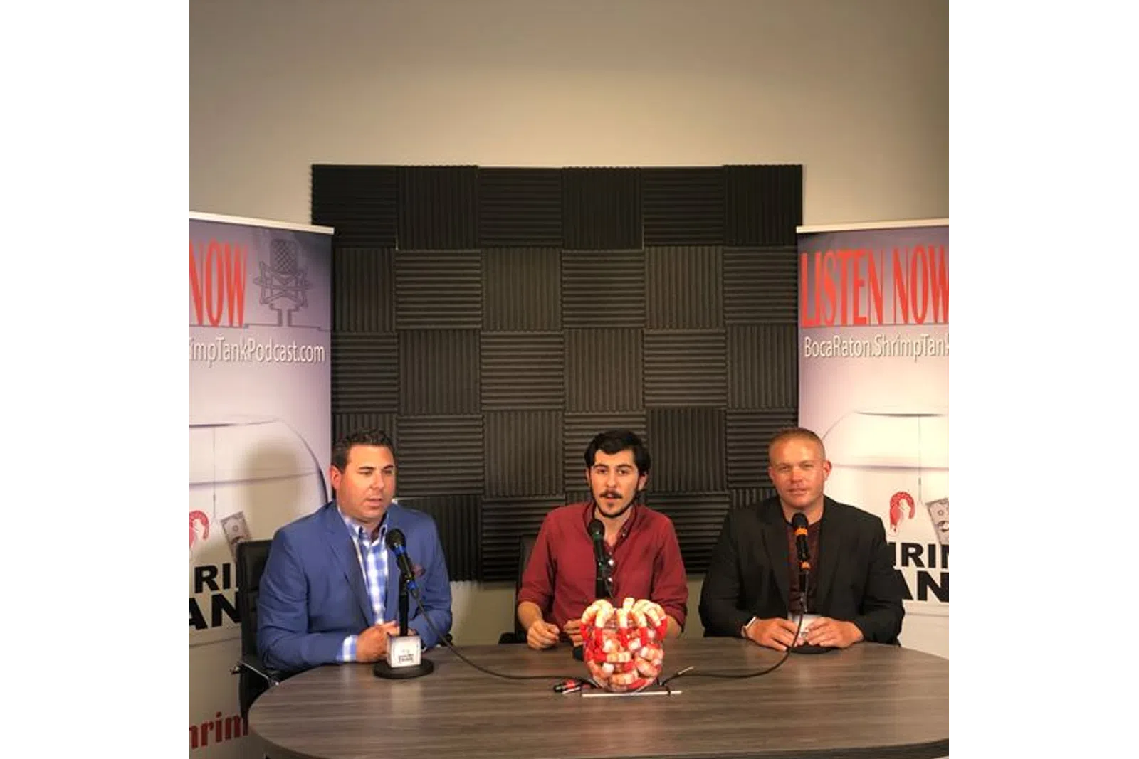 a group of men sitting at a table with microphones