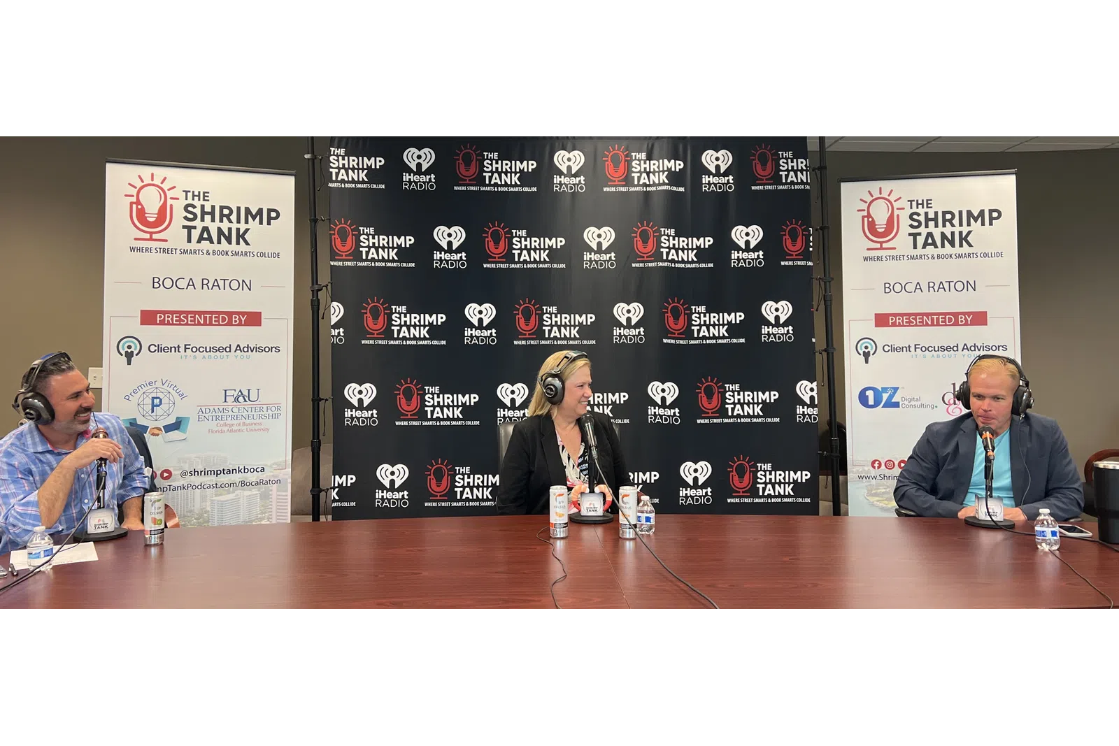 a man and woman sitting at a table with microphones and a sign