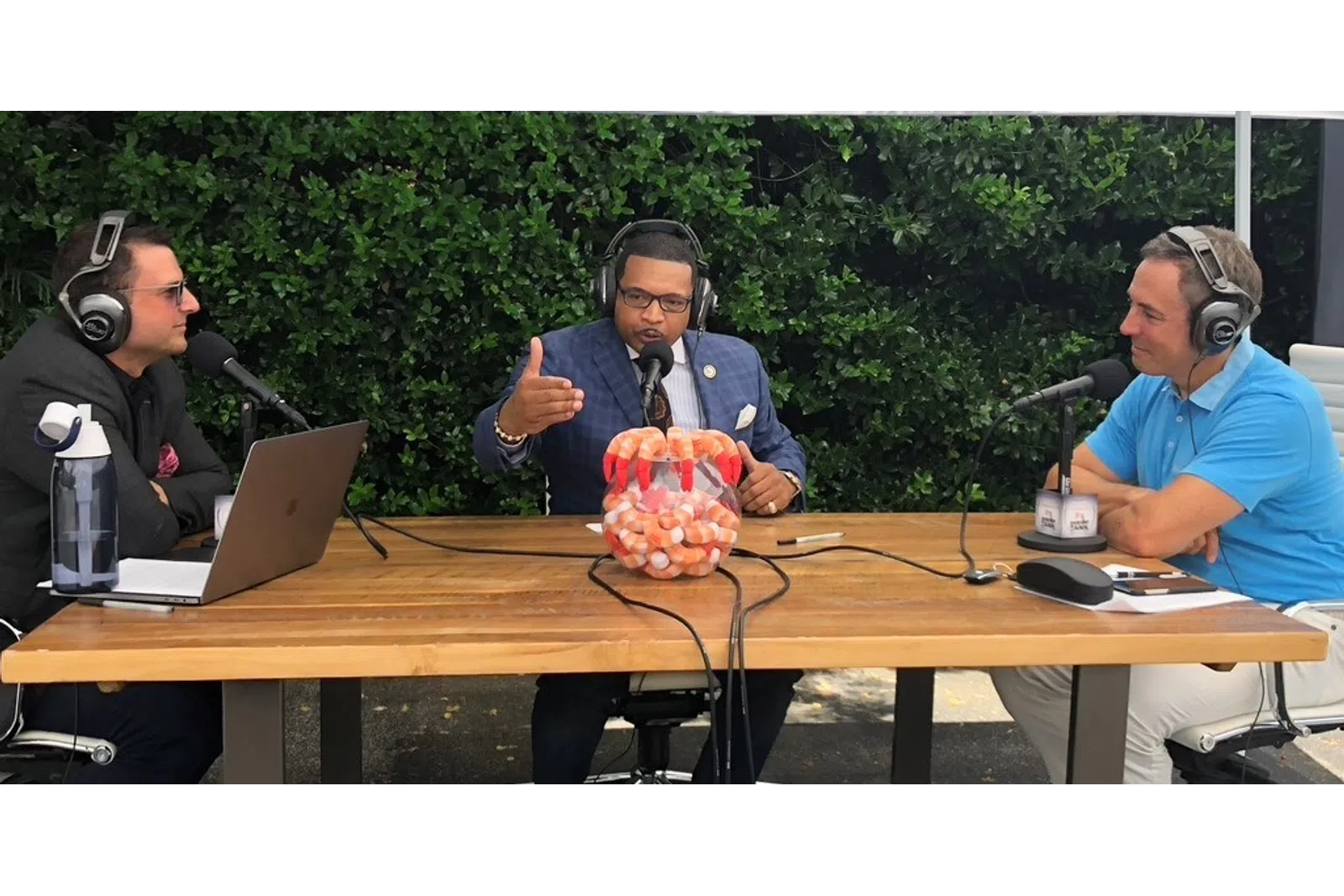 a group of people sitting at a table with microphones and a laptop