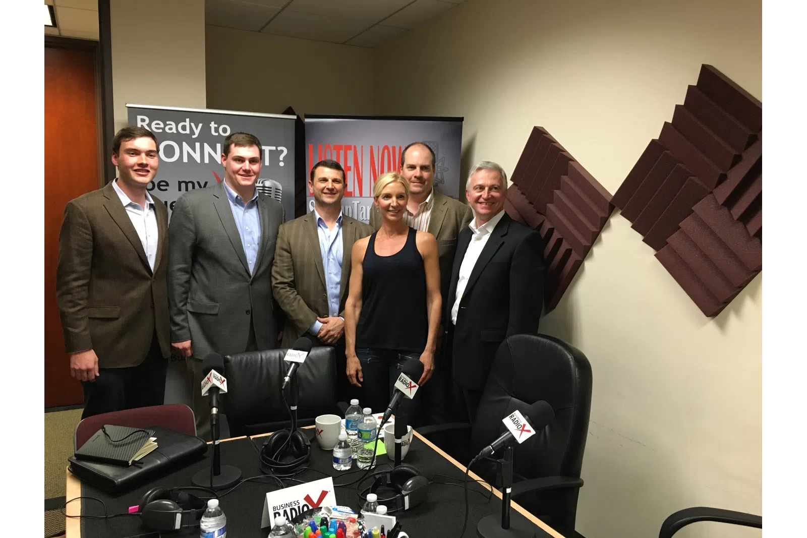 a group of people standing in front of a table with microphones