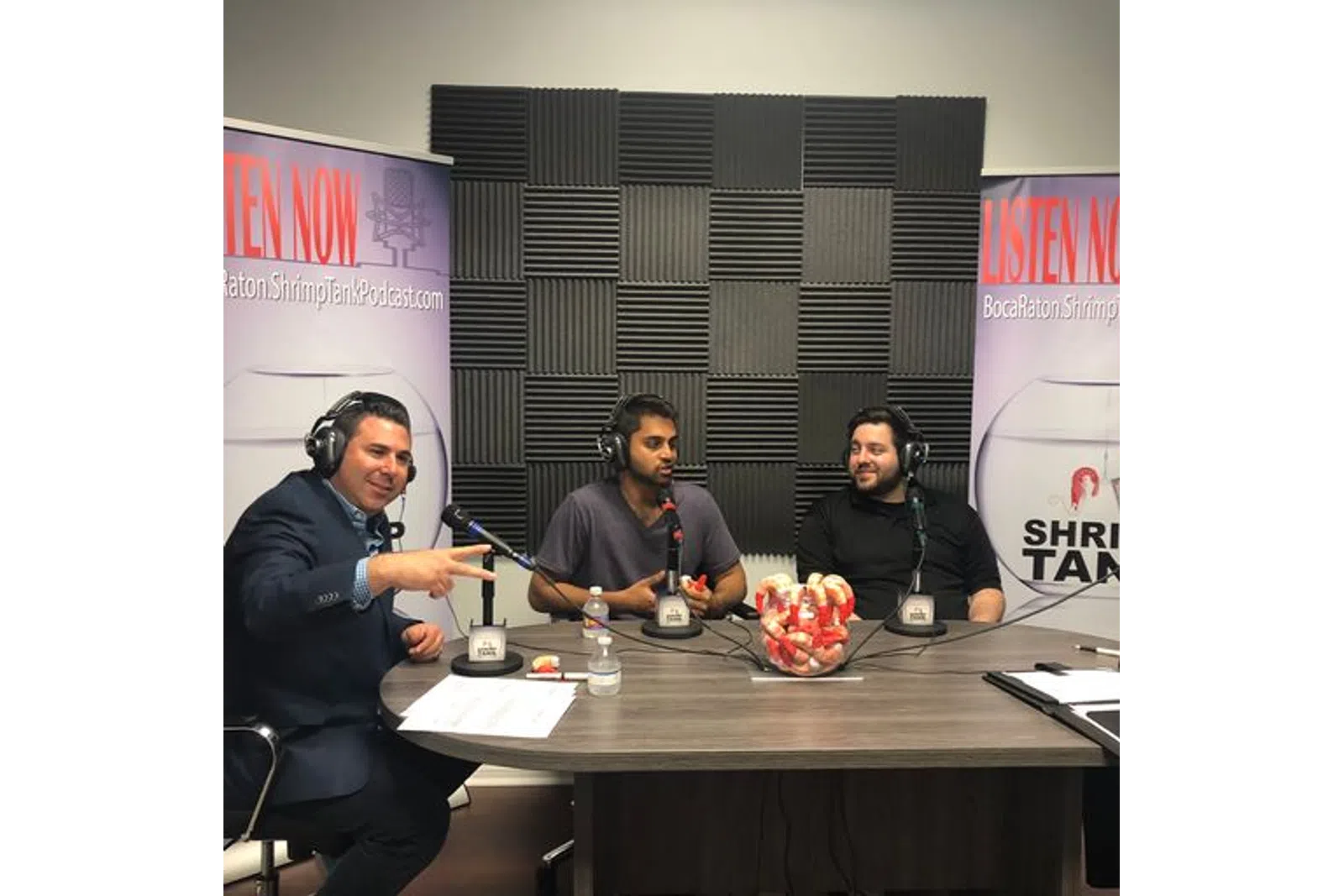 a group of men sitting at a table with microphones and food