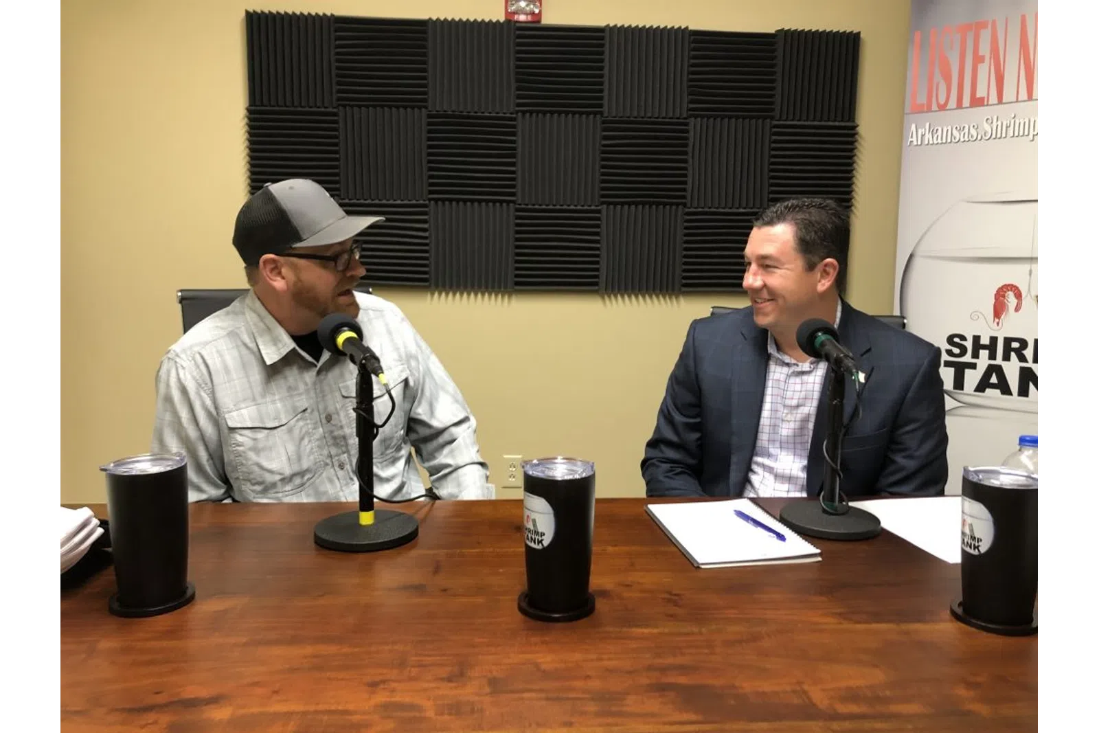 a couple of men sitting at a table with microphones and drinks
