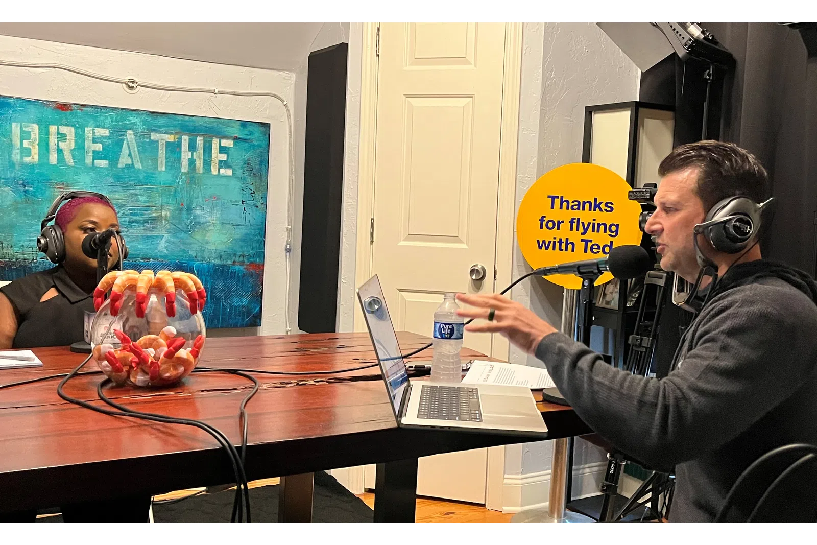 a man wearing headphones and sitting at a table with a laptop