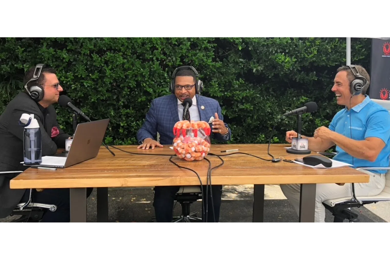 a group of men sitting at a table with microphones and a fruit on it