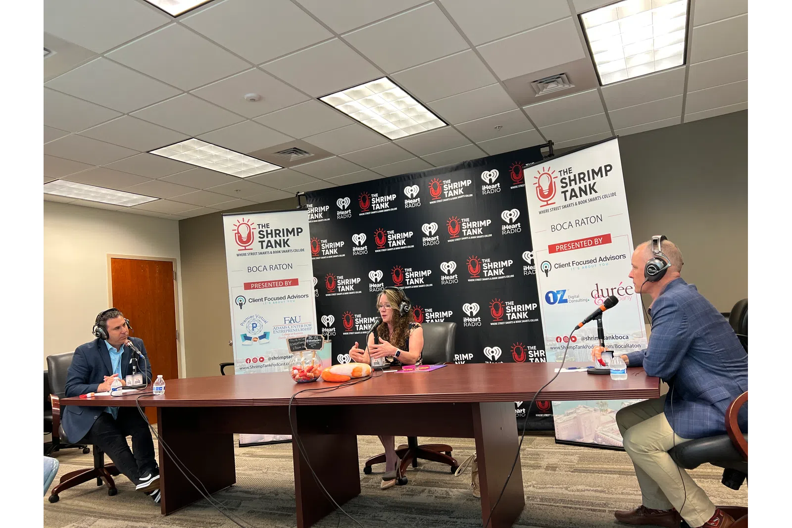 a group of people sitting at a table with microphones and a sign