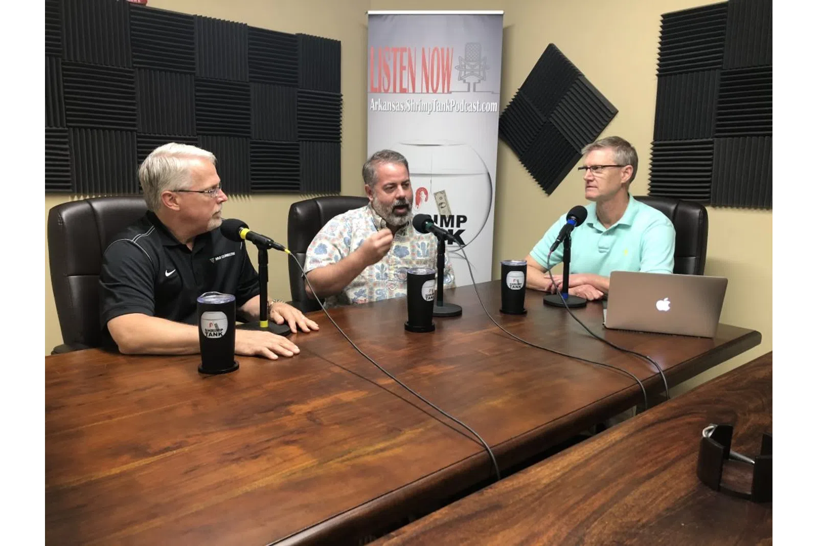 a group of men sitting at a table with microphones