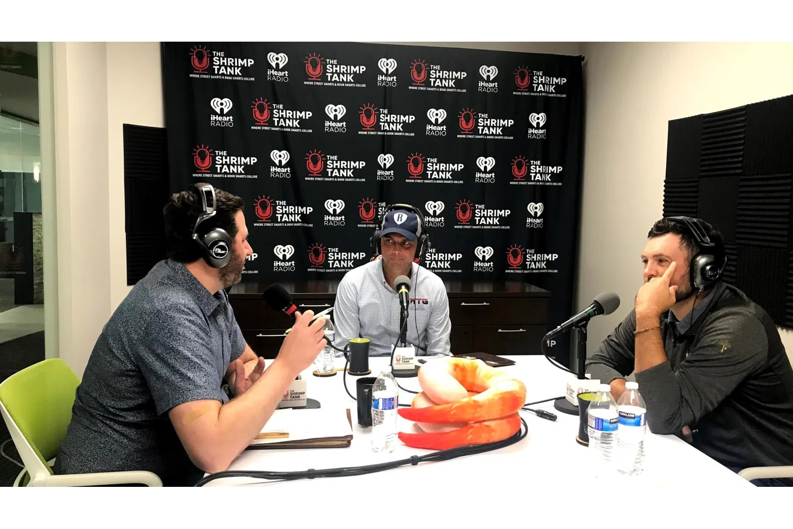 a group of people sitting at a table with food and microphones