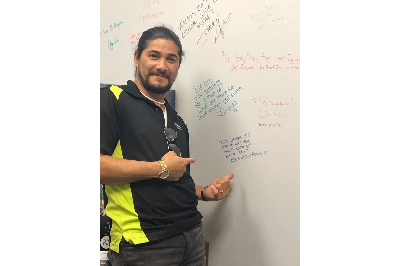 a man with his hand up in front of a whiteboard