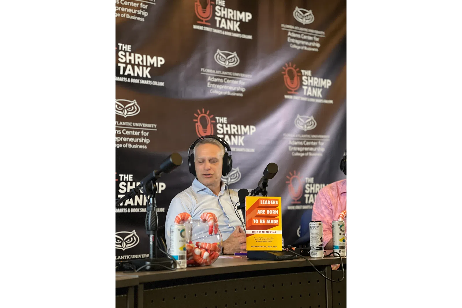 a person wearing headphones and sitting at a desk with a microphone