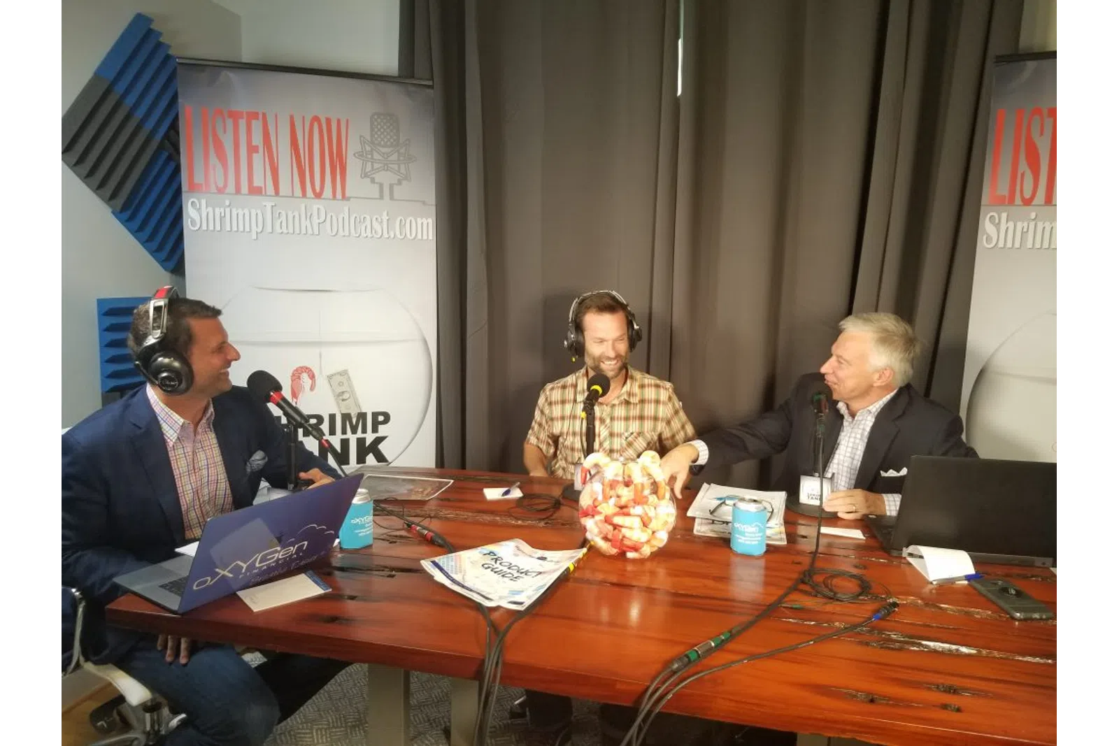 a group of people sitting at a table with laptops and microphones