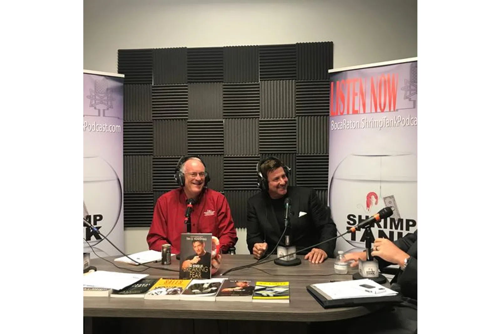 a couple of men sitting at a table with microphones