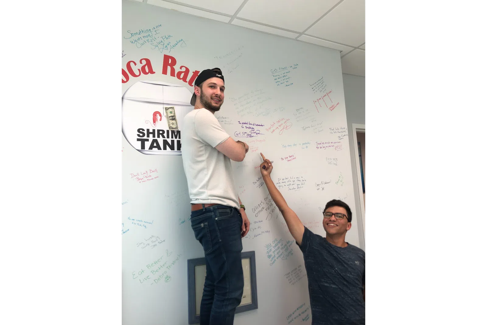 a man and woman standing next to a white board with writing on it