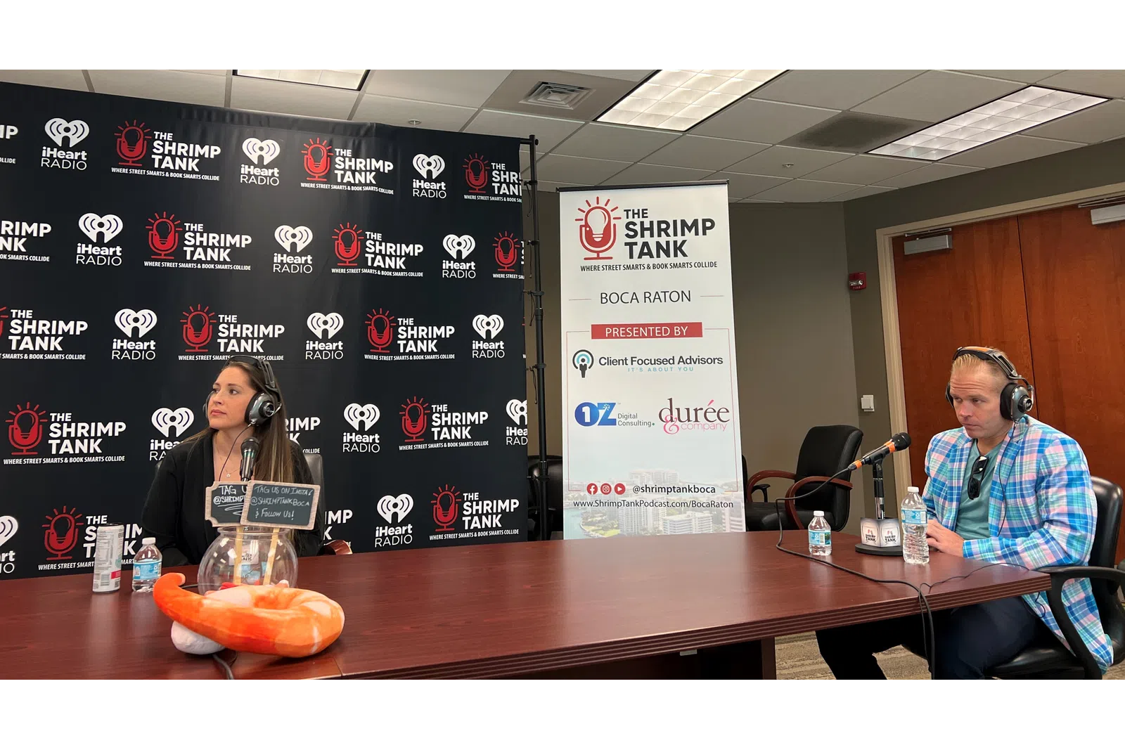 a person sitting at a table with a microphone and a person sitting at a table with a sign