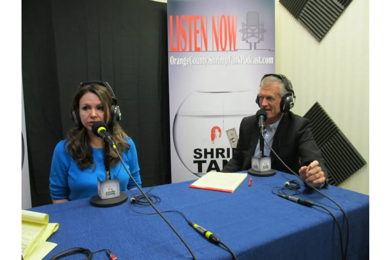a man and woman sitting at a table with microphones