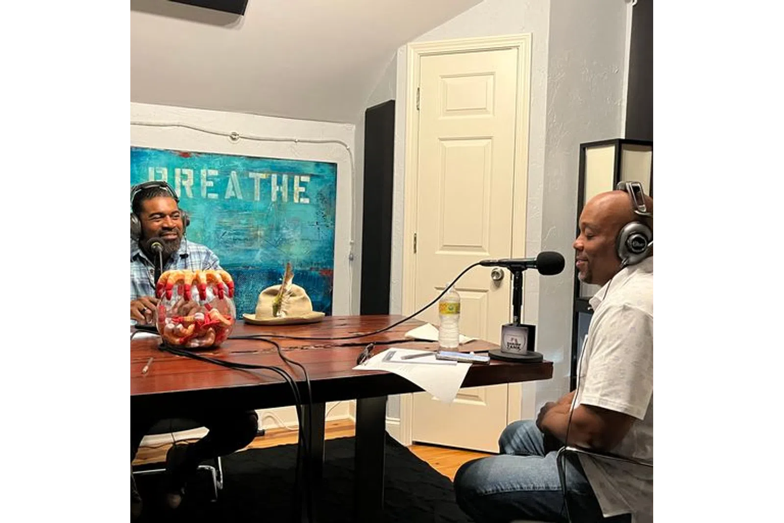 a man wearing headphones and sitting at a table with a man wearing a headset
