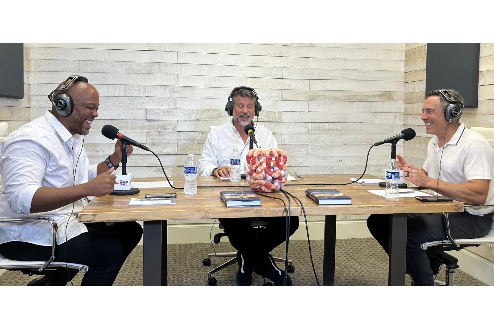 a group of men sitting at a table with microphones and a bag of candy