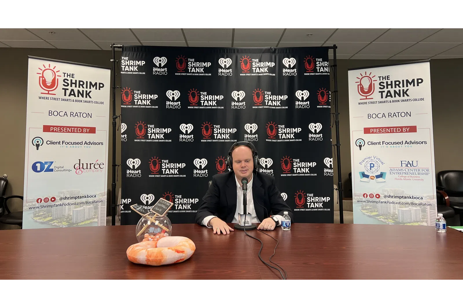 a person sitting at a table with a burger and a sign behind him