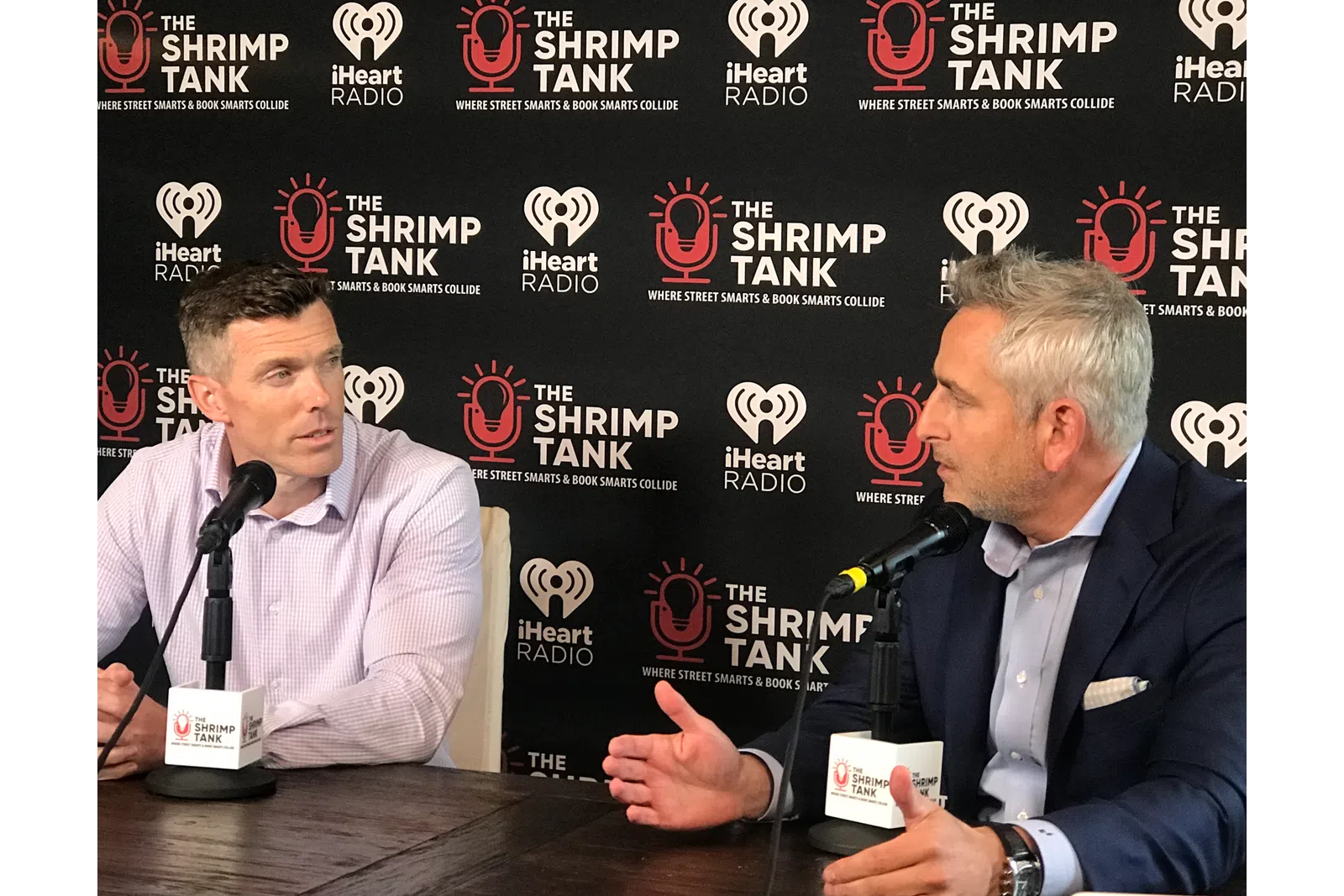 a couple of men sitting at a table with microphones