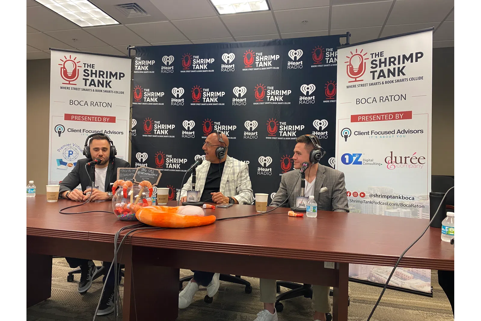 a group of men sitting at a table with microphones and food