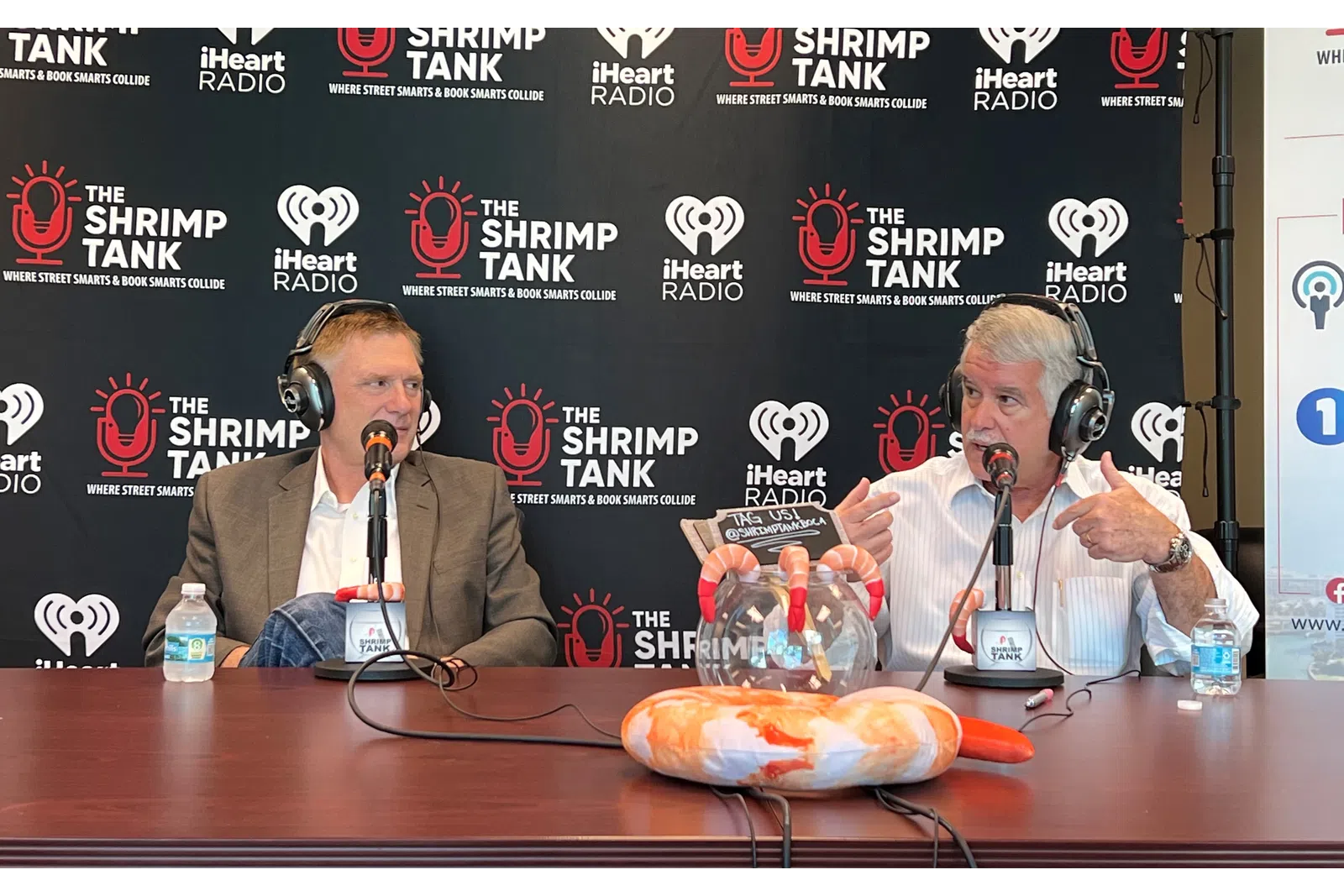 a couple of men wearing headphones and sitting at a table with a plate of food