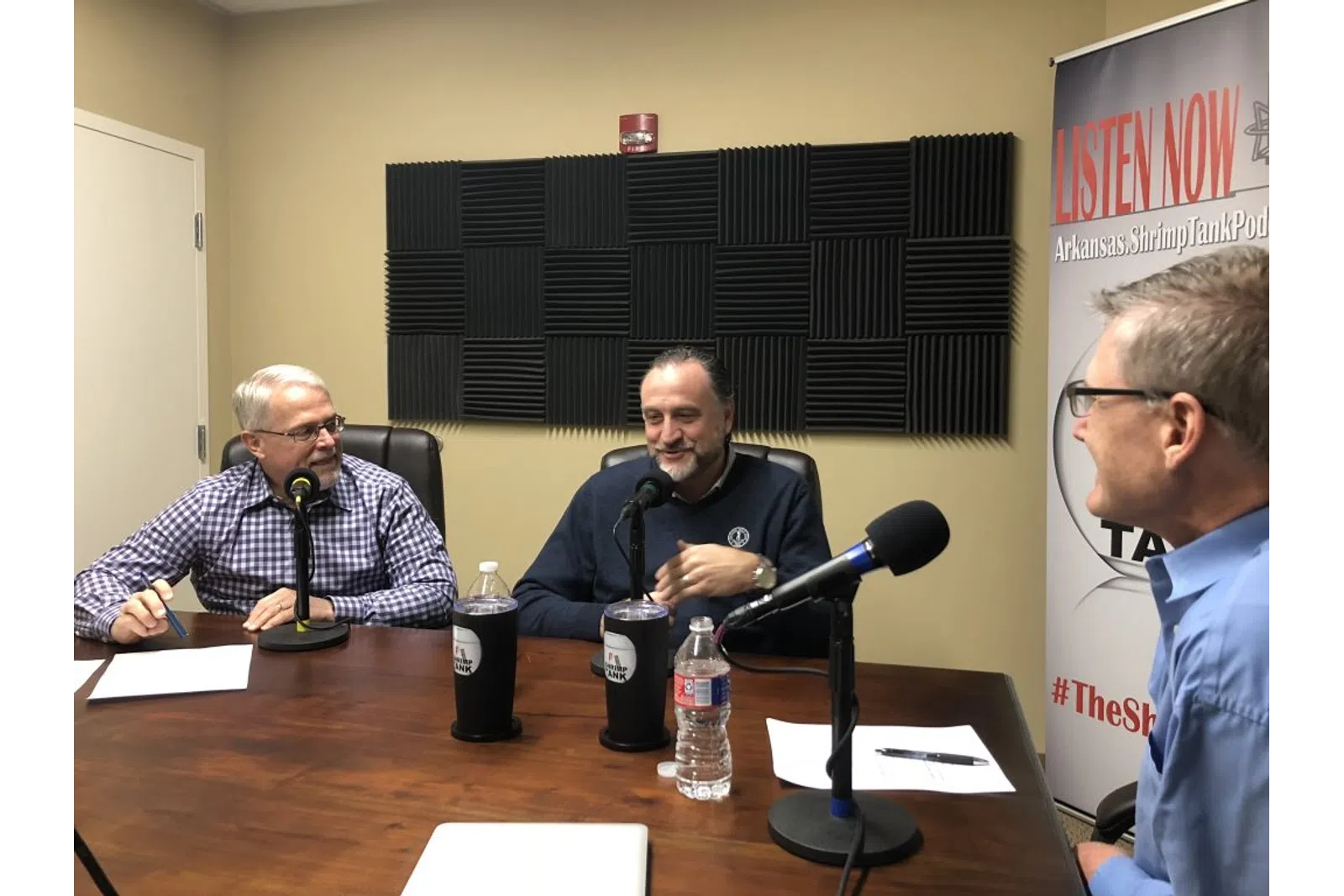 a group of men sitting at a table with microphones
