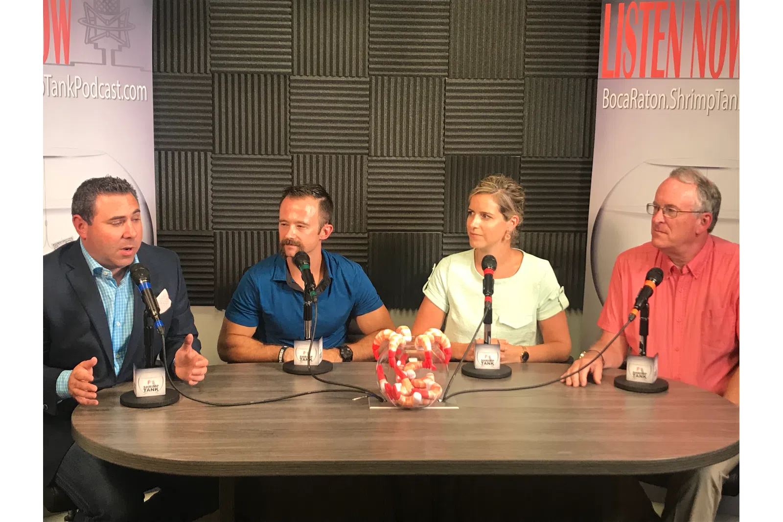 a group of people sitting at a table with microphones
