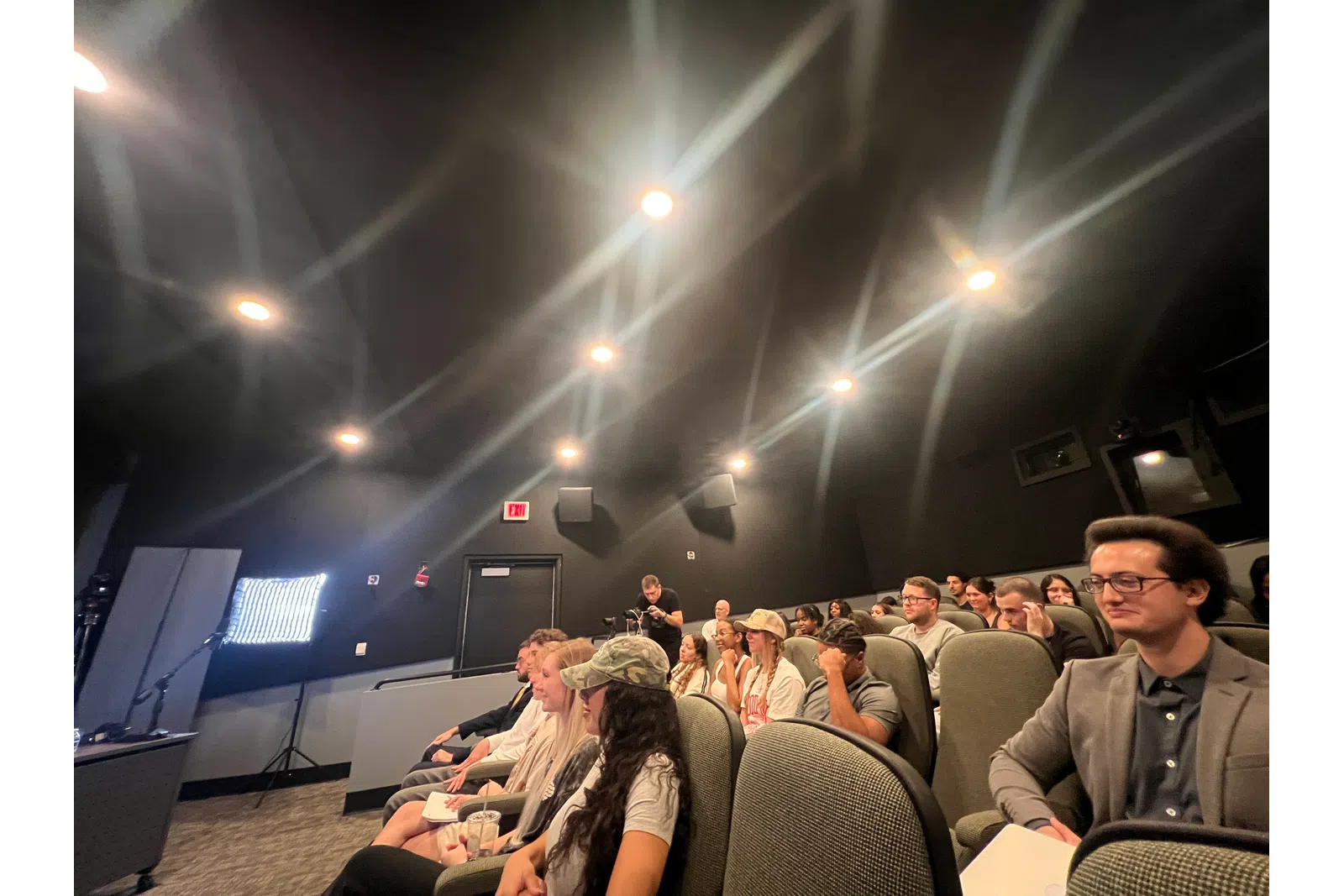 a group of people sitting in a room with a large screen