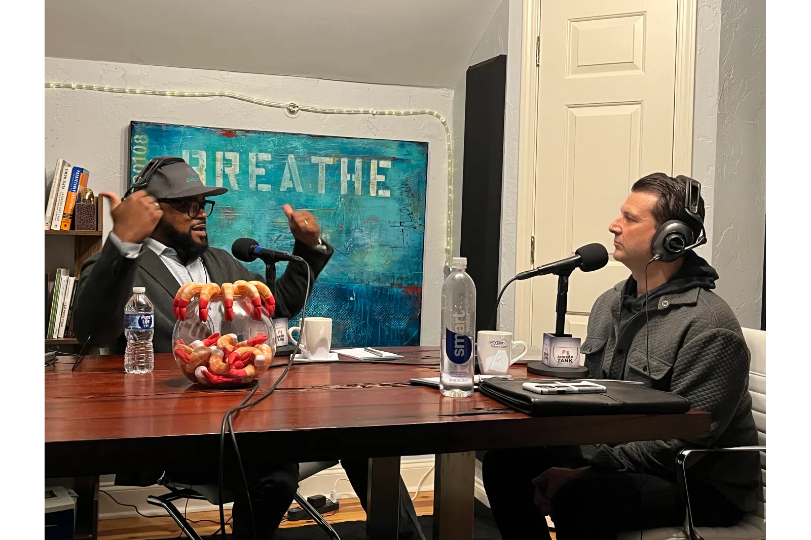 a couple of men wearing headphones and sitting at a table with microphones
