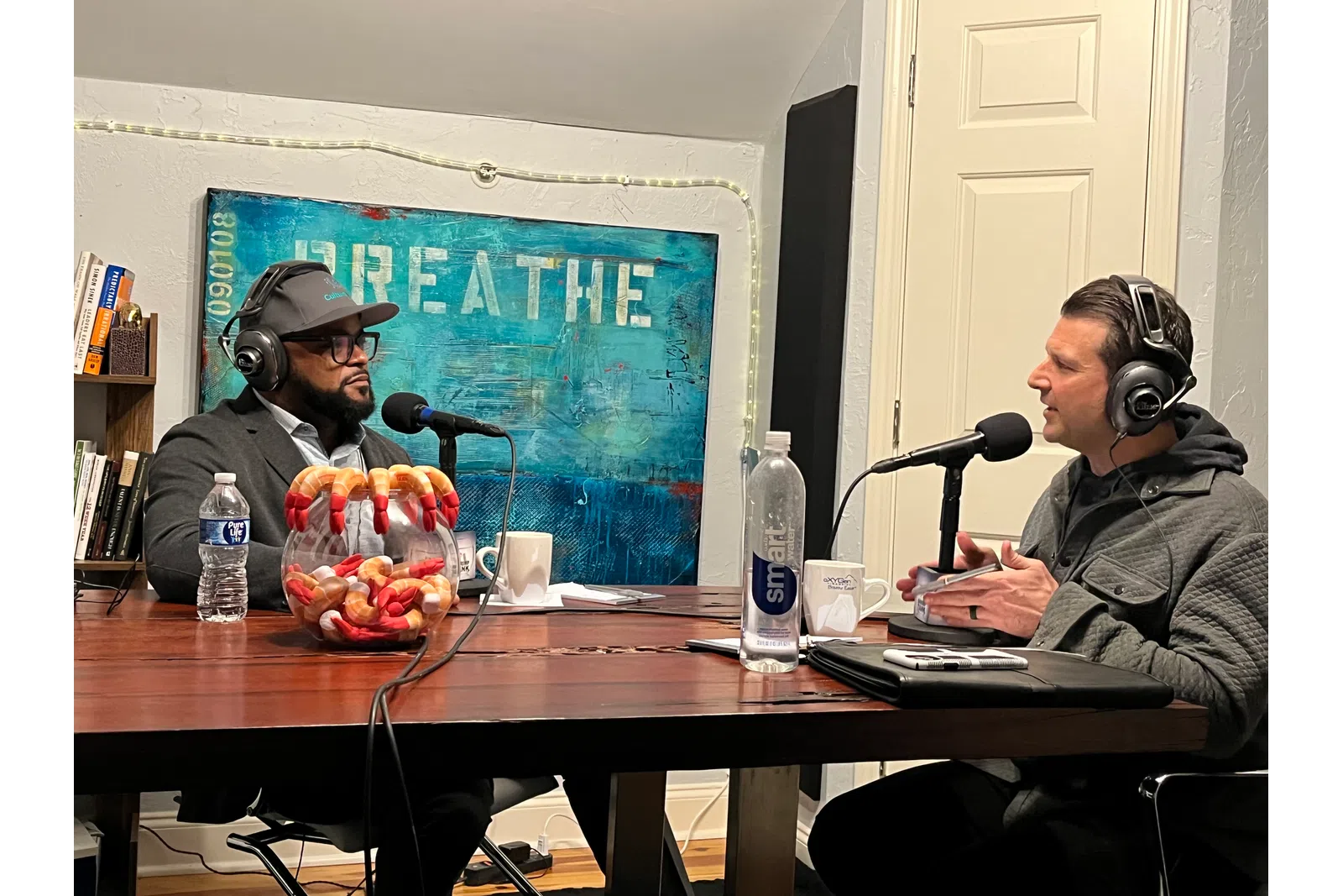 a couple of men wearing headphones and sitting at a table with microphones