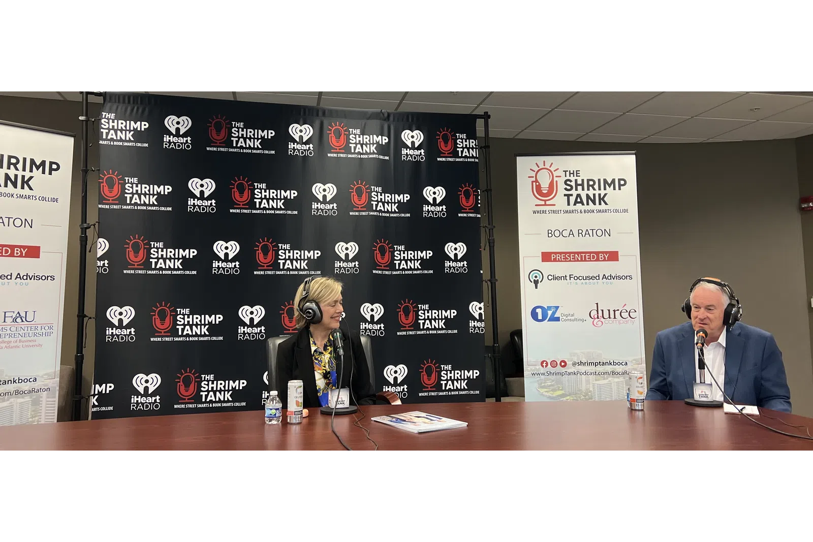 a man and woman sitting at a table with microphones